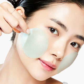 Visage feminin avec papier matifiant bleu sur la joue montrant le resultat anti-pores Medicube Zero Pore Serum