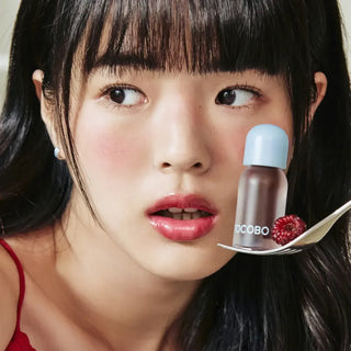 Tocobo Juicy Berry Lip Oil - mannequin aux levres brillantes tenant le flacon avec framboise