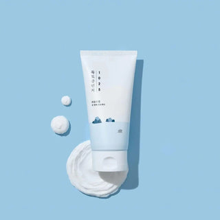 Tube ROUND LAB 1025 Dokdo Cleanser pose sur fond bleu avec cotons et mousse