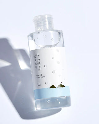 Flacon ROUND LAB 1025 Dokdo Toner 200ml incline avec gouttes d'eau sur le verre