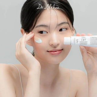 Femme appliquant la crème Dr.Althea 147 Barrier Cream sur sa pommette, tube blanc à la main