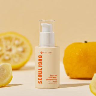 Flacon Seoul 1988 Glow Serum K-Secret entoure de tranches de citron et de fruits yuja sur fond beige