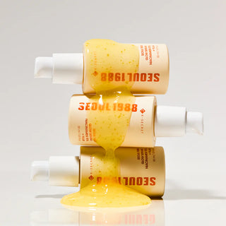Trois flacons Seoul 1988 Glow Serum K-Secret empiles avec serum jaune dore coulant entre les flacons