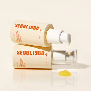 Deux flacons Seoul 1988 Glow Serum K-Secret superposes avec goutte doree coulant de la pompe