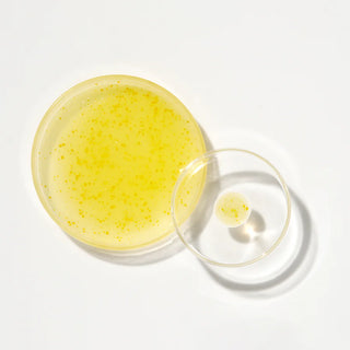 Texture jaune doree du Glow Serum K-Secret avec micro-capsules dans deux coupelles en verre, vue du dessus