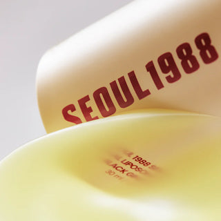 Gros plan sur le flacon KSECRET Seoul 1988 baignant dans du serum retinal jaune dore en macro