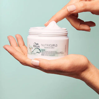 Wella Nutricurls Mask - mains ouvrant le pot montrant texture epaisse blanche sur fond menthe