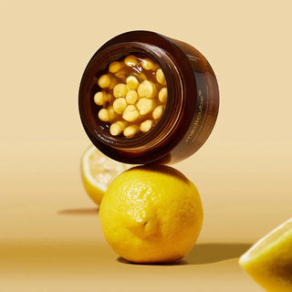 Pot ouvert Medicube Deep Vita C Capsule Cream pose sur un citron entier, fond jaune pastel