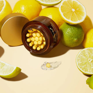 Medicube Deep Vita C Capsule Cream pot ouvert entoure de citrons et citrons verts sur fond jaune