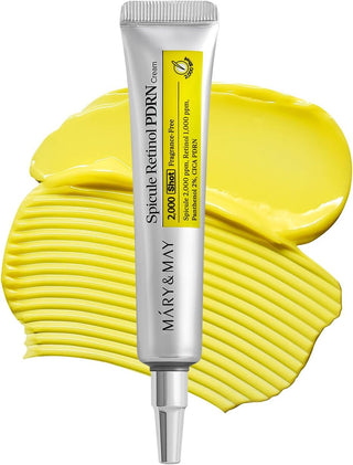 Tube argenté MARY&MAY Spicule Retinol PDRN Cream sur swatch de crème jaune - rétinol 1000 ppm, spicules 2000 ppm