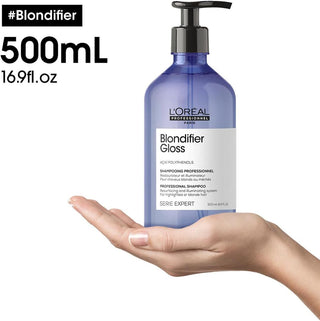 Main tenant le flacon pompe 500ml L'OREAL PROFESSIONNEL Blondifier Gloss - taille reelle visible