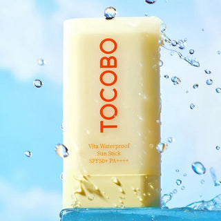 Stick solaire TOCOBO Vita Waterproof sous des éclaboussures d'eau sur fond ciel - formule résistante à l'eau