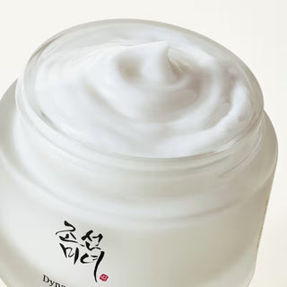 Gros plan de la texture crème blanche onctueuse dans le pot ouvert Dynasty Cream