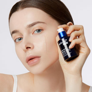 Mannequin au teint lumineux tenant le flacon Medicube Zero Pore One Day Serum avec goutte de serum sur la joue