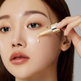 Application du serum Medicube Deep Vita C Ampoule a la pipette sur la joue, gouttes dorees visibles
