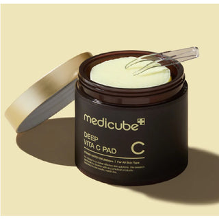 Pot ouvert Medicube Deep Vita C Pad avec pince et pad jaune imbibe visible sur fond beige