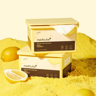 MEDICUBE Deep Vita C Daily Quick Mask - deux boites jaunes empilees avec citrons sur fond de poudre jaune