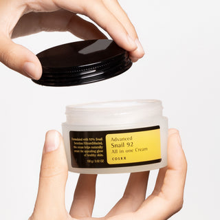 COSRX Snail 92 All In One Cream - mains ouvrant le pot, texture creme blanche onctueuse visible