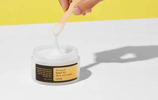 COSRX Snail 92 Cream - spatule en bois soulevant la creme filante depuis le pot ouvert