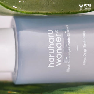 Haruharu Wonder Black Rice Hyaluronic Essence - gros plan flacon bleu entre des feuilles vertes, label PETA Approved