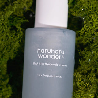 Haruharu Wonder Black Rice Hyaluronic Essence - flacon bleu-gris pose sur de la mousse verte naturelle