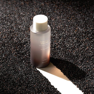 Haruharu Wonder Black Rice Hyaluronic Toner - flacon violet pose sur des grains de riz noir en gros plan