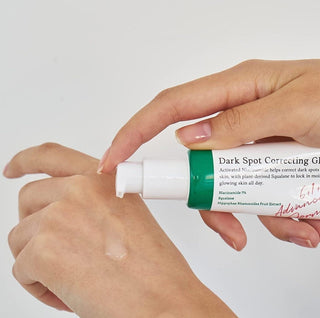 Main appliquant le serum AXIS-Y Dark Spot Correcting Glow Serum sur le dos de la main, goutte transparente visible