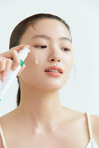 Modele appliquant le serum AXIS-Y Dark Spot Correcting Glow Serum sur la joue, peau eclatante