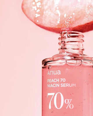 ANUA Peach 70 Niacin Serum - gros plan du col du flacon avec tranche de peche et gouttelettes