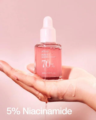 ANUA Peach 70 Niacin Serum - flacon rose tenu dans une main mouillee, formule 5% niacinamide