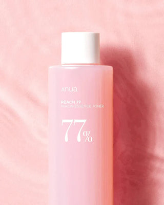 Flacon rose ANUA Peach 77 Niacin Essence Toner sur tissu rose avec ombre portee naturelle