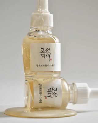 Deux flacons Beauty of Joseon Glow Serum Propolis empiles avec serum dore qui coule sur les parois