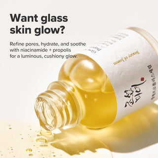 Flacon Beauty of Joseon Glow Serum Propolis couche sur le cote, serum dore versant sur fond creme