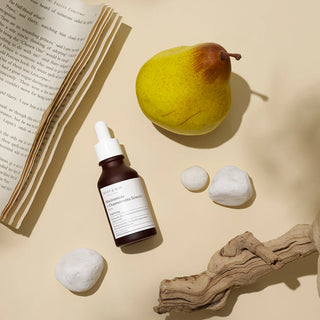MARY&MAY Niacinamide Chaenomeles Serum - vue du dessus avec poire, livre ouvert et bois flotte sur fond beige