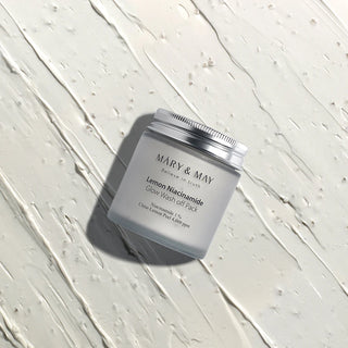 MARY&MAY Lemon Niacinamide Wash Off Pack - pot ferme sur fond de texture cremeuse blanche etalee
