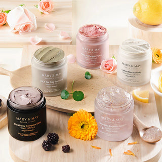 Collection MARY&MAY de cinq masques wash off ouverts sur plateau bois avec roses, mures et citron