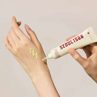 Application du Seoul 1988 Eye Cream K-Secret sur le dos de la main, texture jaune-vert en zigzag