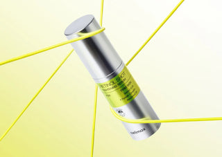 Flacon argente Celimax Retinol Shot Tightening Serum incline sur fond jaune avec fils elastiques