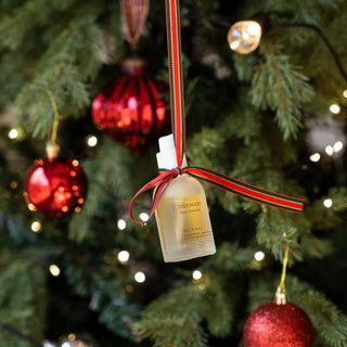 Flacon Mixsoon Bean Essence suspendu a un sapin de Noel avec ruban rouge et vert, boules decoratives