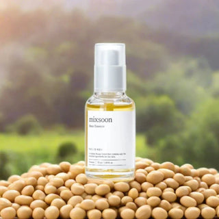 Flacon Mixsoon Bean Essence pose sur un lit de graines de soja avec vegetation verte en arriere-plan