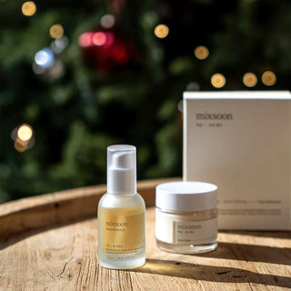Duo Mixsoon Bean Essence et Bean Cream poses sur table en bois avec lumieres festives en arriere-plan
