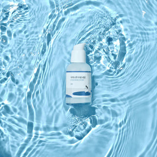 Flacon Round Lab Birch Juice Serum immerge dans de l'eau avec bulles et ondulations turquoise