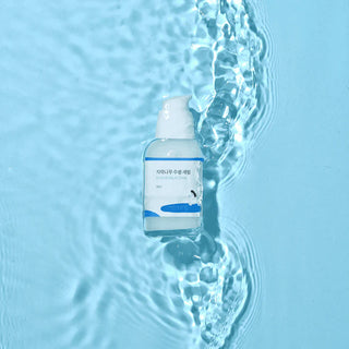 Flacon Round Lab Birch Juice Moisturizing Serum 50ml pose dans de l'eau claire sur fond bleu