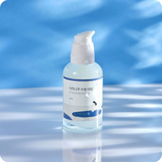 Flacon Round Lab Birch Juice Moisturizing Serum pose sur fond bleu aquatique