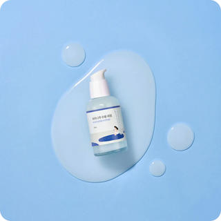 Flacon pompe Round Lab Birch Juice Serum vu du dessus dans une goutte de texture sur fond bleu
