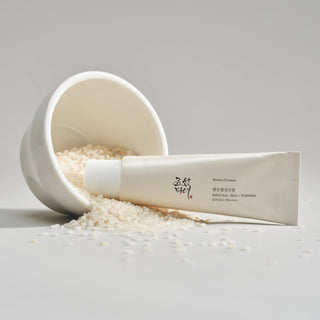 Beauty of Joseon Relief Sun - tube beige pose contre un bol renverse rempli de grains de riz blanc