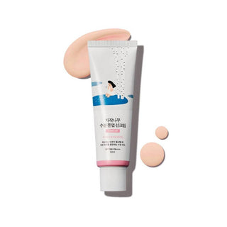 Round Lab Birch Tone-Up Sunscreen avec texture rose clair onctueuse deposee autour du tube