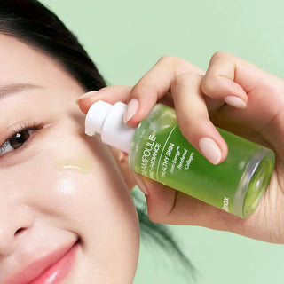 Application de la CELIMAX Noni Ampoule au compte-gouttes sur la joue, serum vert translucide