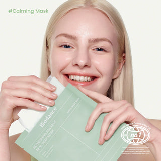 Modele blonde souriante tenant le sachet BIODANCE Sea Kelp Real Deep Mask pres de son visage lumineux