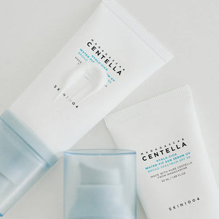 Deux tubes SKIN1004 Hyalu-Cica Sun Serum SPF50+ couches a plat avec capuchon bleu et swatch de texture blanche